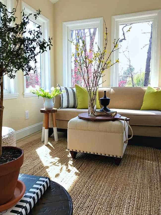 small sunroom with sectional sofa and an ottoman for a coffee table