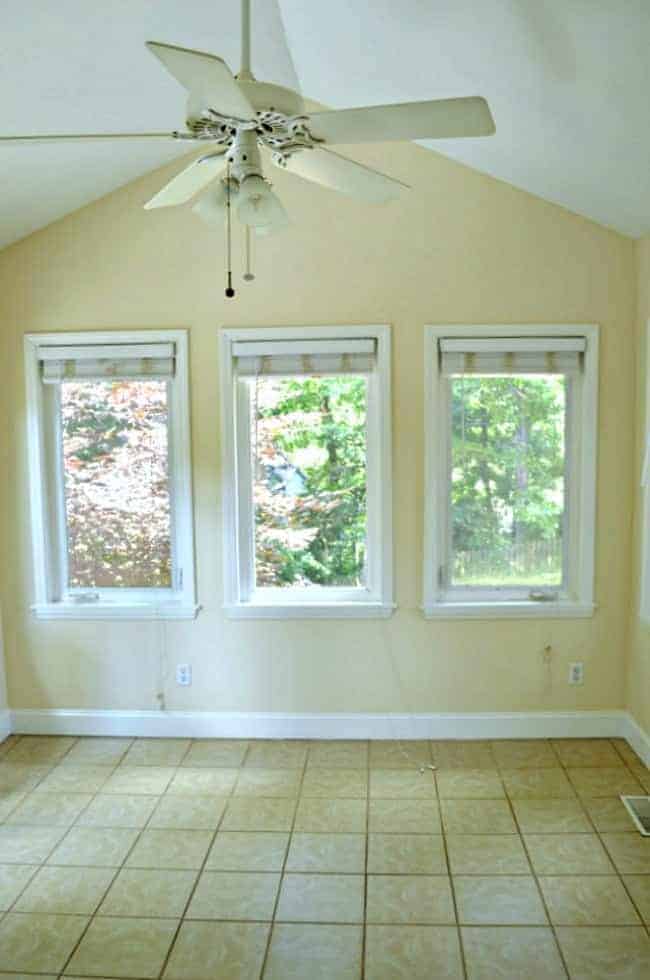 A sunroom makeover before pic of the yellow walls and broken ceiling fan.