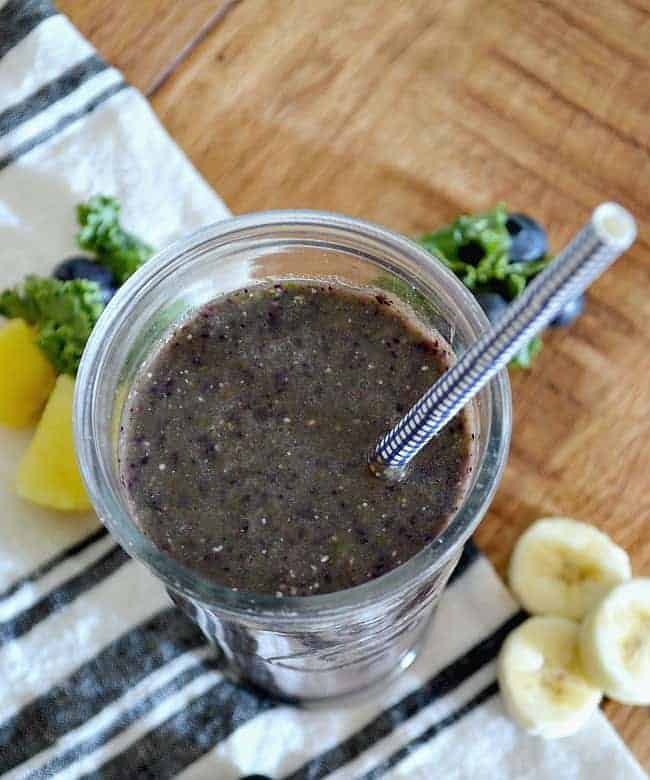 top view of a kale blueberry smoothie with a blue straw 