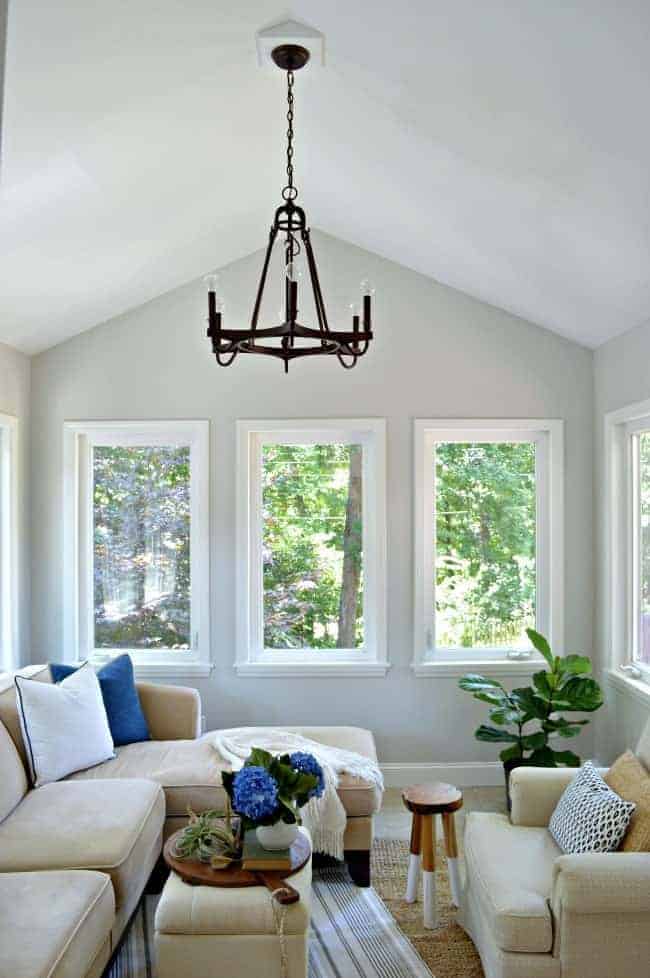 view of sunroom with painted gray walls, new hanging light and sectional sofa decorated in blue pillows