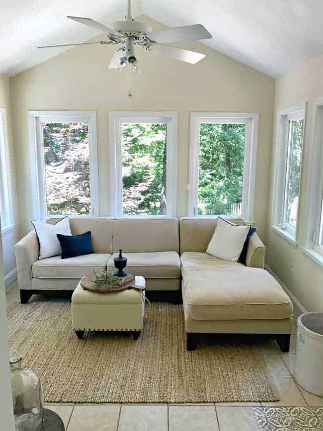 view of sunroom with vaulted ceiling, white ceiling fan and beige sectional sofa