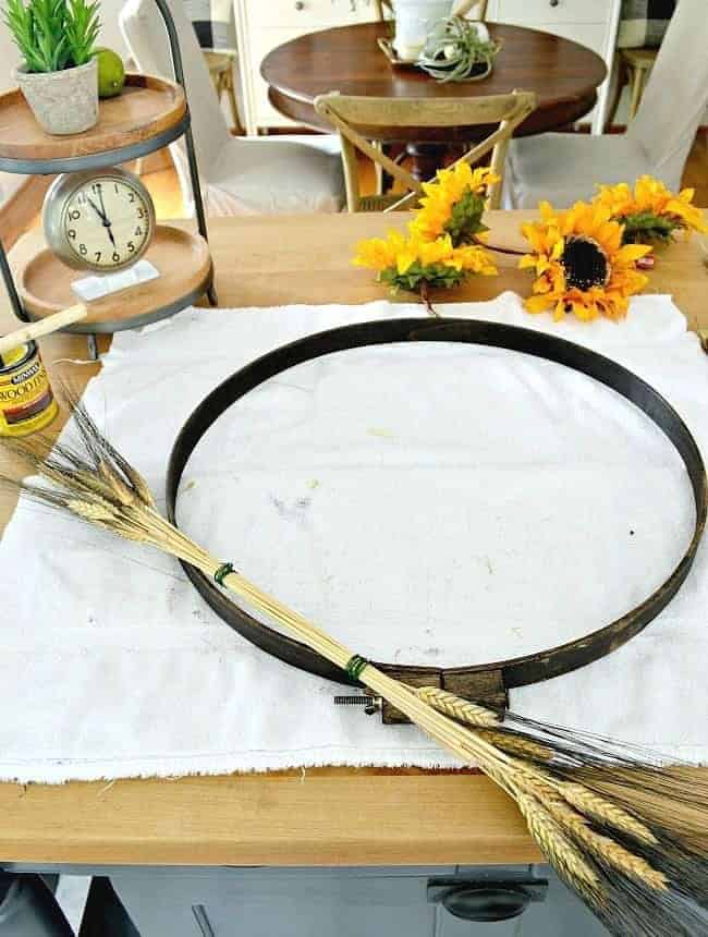 Adding tied wheat to an embroidery hoop to create a simple DIY fall front door wreath. 