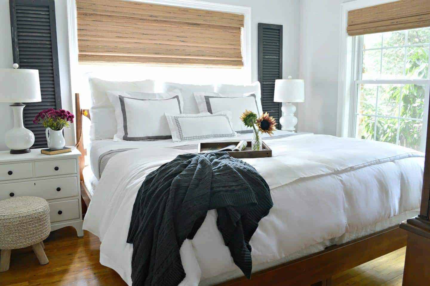 view of master bedroom with king size bed dressed with white linens and old wooden shutters hanging on wall next to window