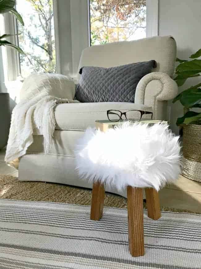 fur stool in sunroom with book and glasses on top