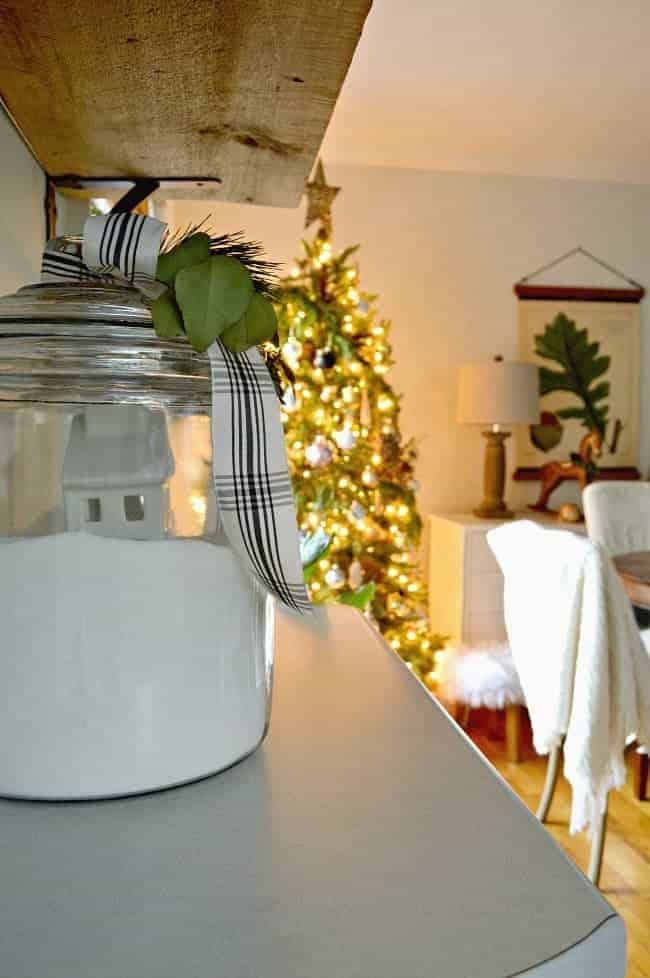 How to create a cozy cottage Christmas kitchen by using farmhouse touches like fresh greenery from the yard and black and white ribbon.