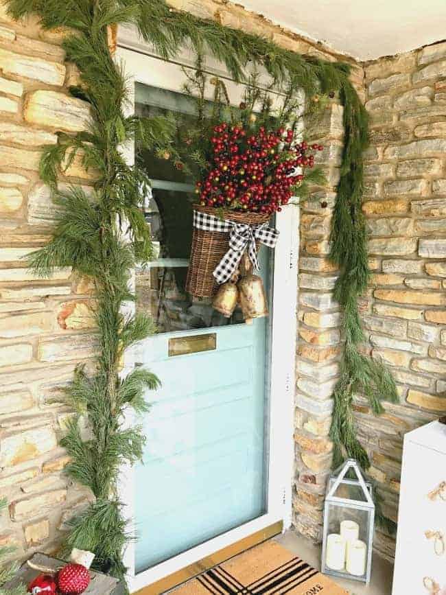 front door decorated with live garland and basket of berries