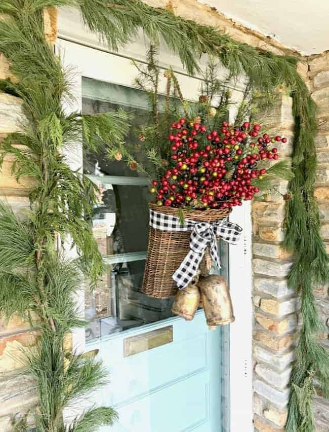 How to create a simple DIY Christmas front door basket, with bells and black buffalo check ribbon, to add holiday color and style to your front door.