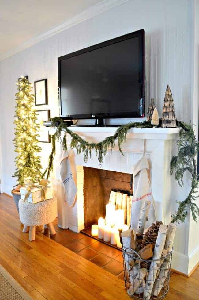 christmas living room with fireplace with tv on mantel