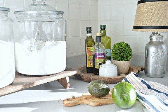 A close up of a cutting board and bottles of oil on the counter,