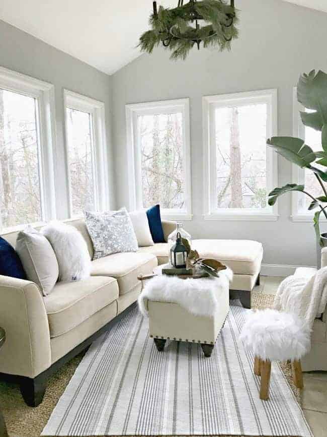 view of beige sectional sofa with pillows, a striped rug and a small ottoman