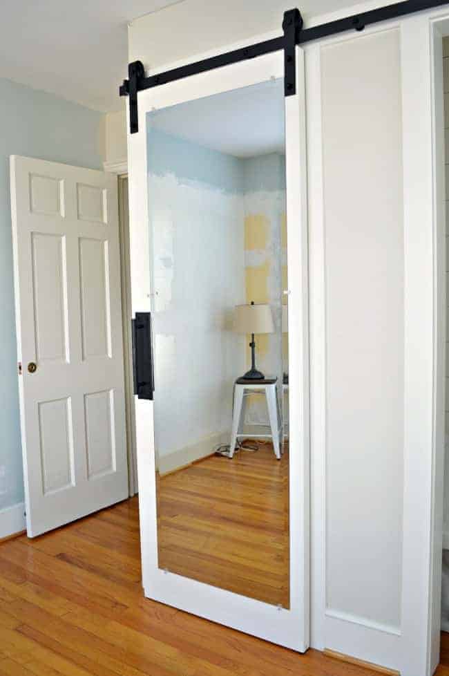 hanging white mirrored barn door on bedroom closet