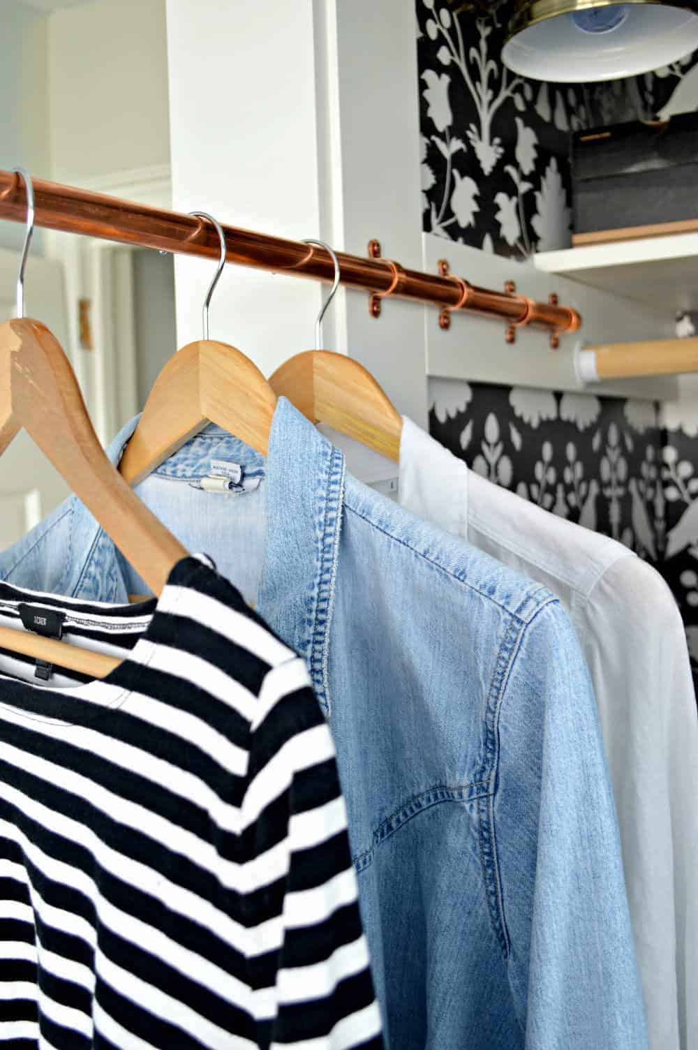 clothes hanging on an extended DIY copper pipe sliding clothes rod in a closet