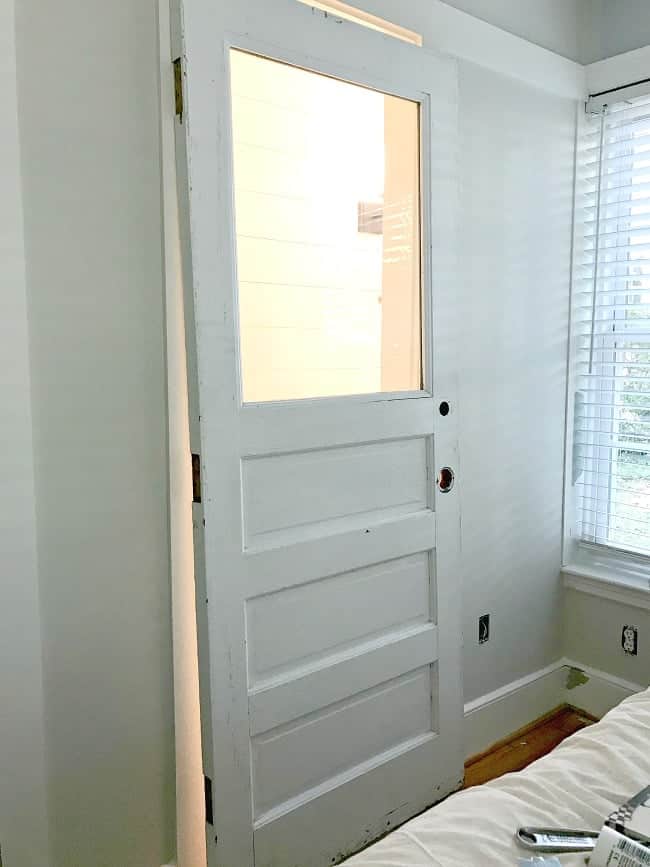 old white door propped up in opening to powder room 