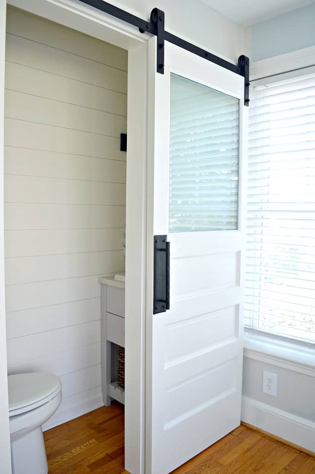 small powder room with a white painted barn door with frosted glass window 