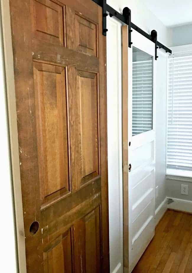 an old wooden door and white door hung with barn door hardware