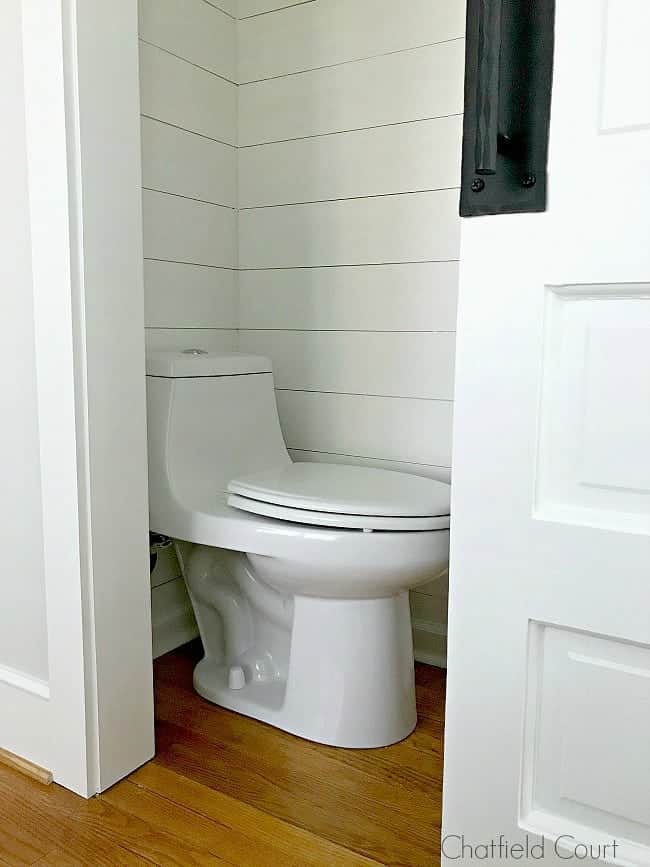 toilet in small powder room with shiplap walls