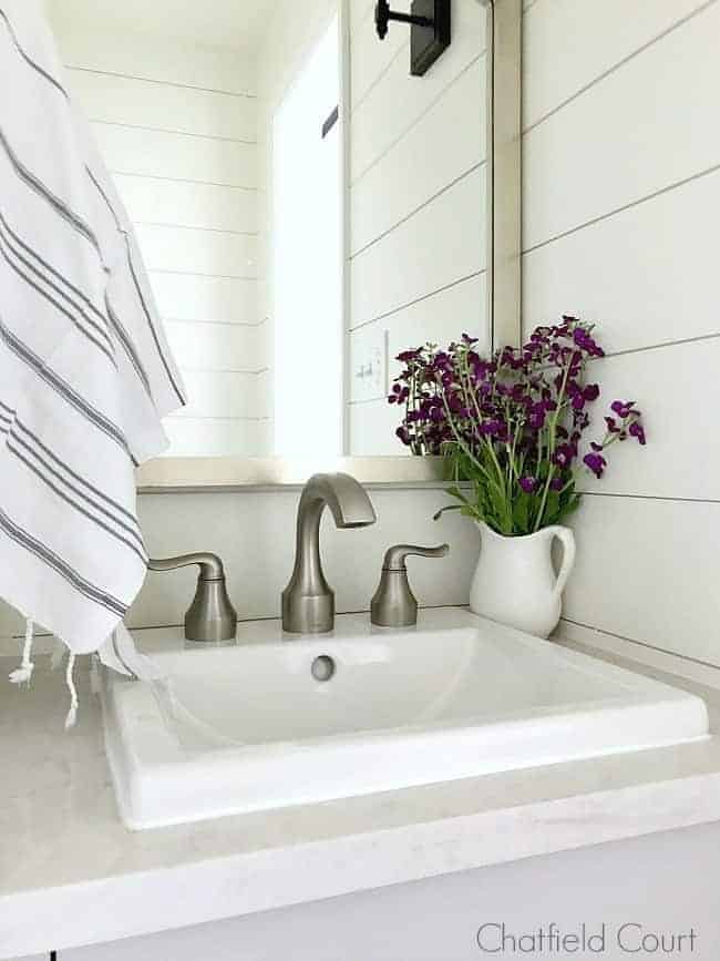 DIY farmhouse bathroom vanity with small pitcher of purple flowers and striped towel