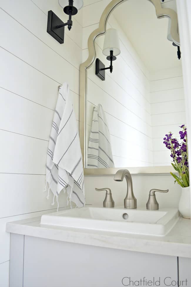 The best white paint colors and a small powder room with gray vanity and silver mirror