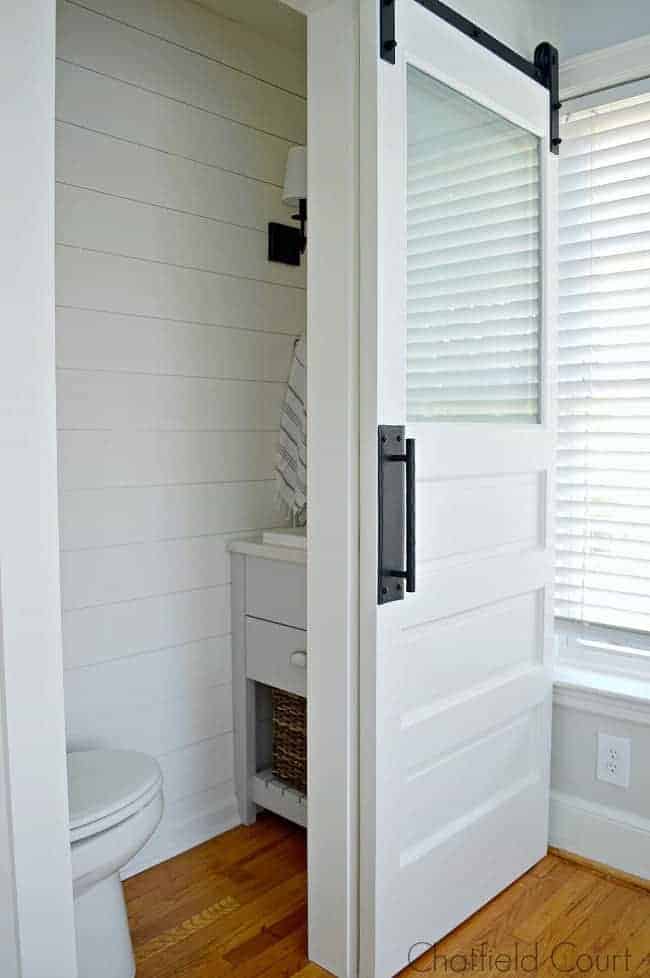 looking in the doorway of tiny powder room with shiplap on the walls