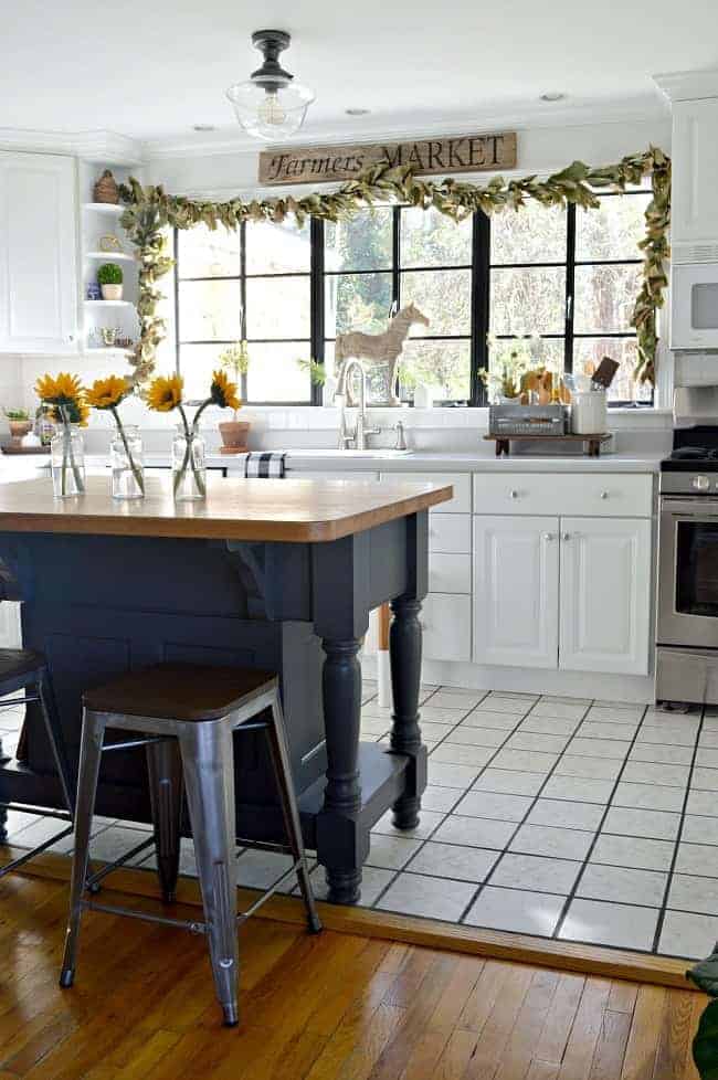 3 clear bottles on a kitchen island wit sunflowers in them