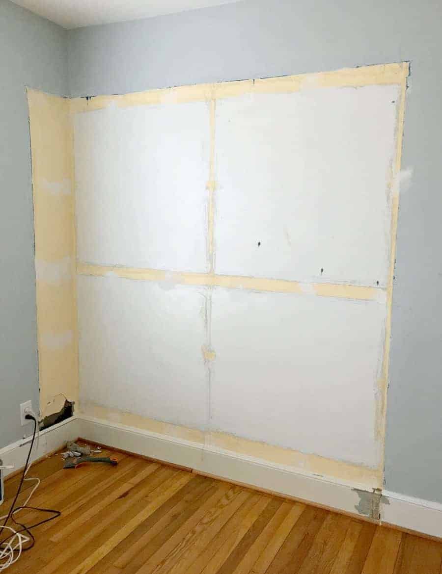 damaged wall in blue bedroom with holes and spackle 