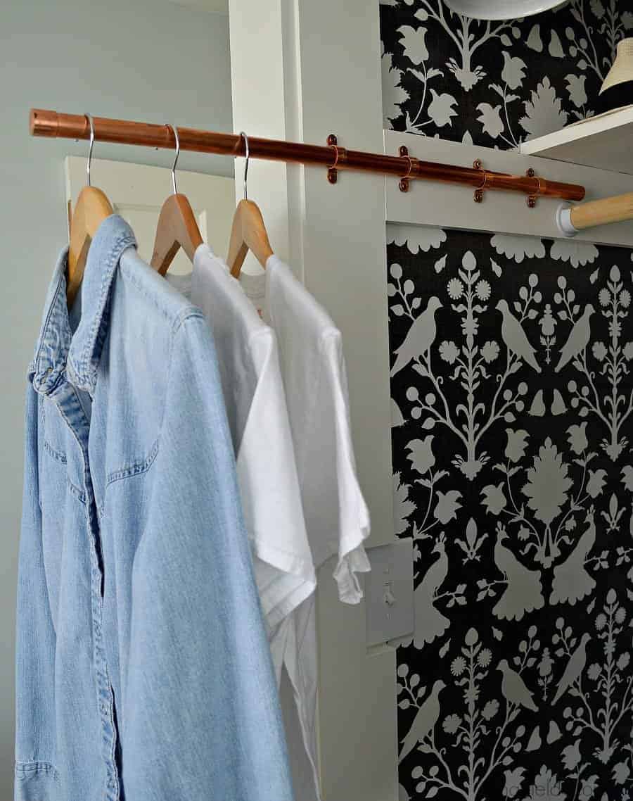 clothes hanging on a DIY copper pipe sliding clothes rod in a closet