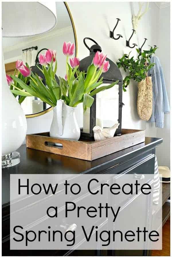 pink tulips in white pitcher and a lantern on black cabinet 