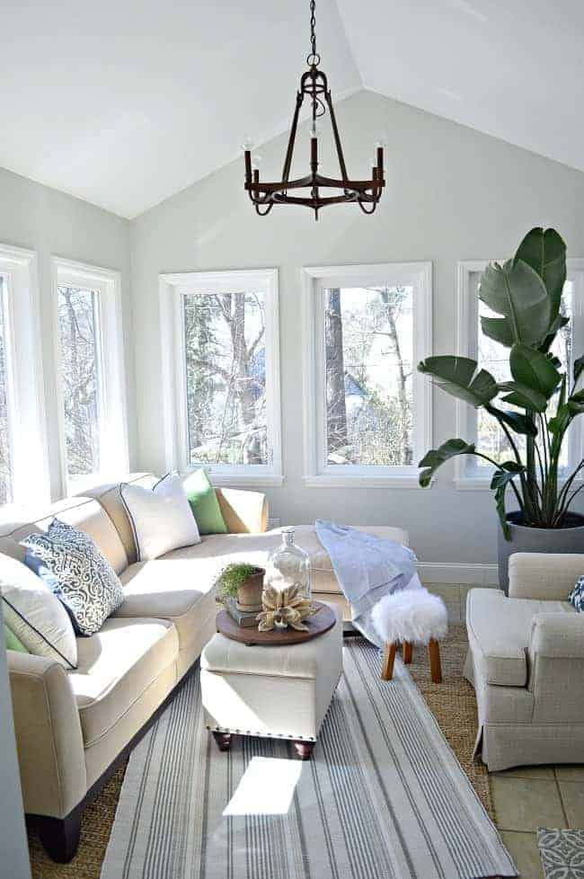 sunroom with lots of windows and sectional sofa with blue and green pillows