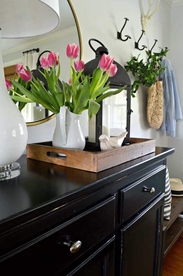 white pitcher filled with pink tulips on entryway console