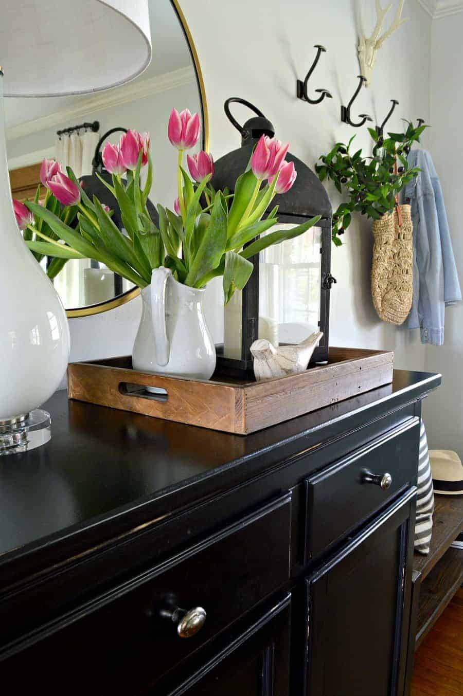 A vase of flowers on an entryway cabinet