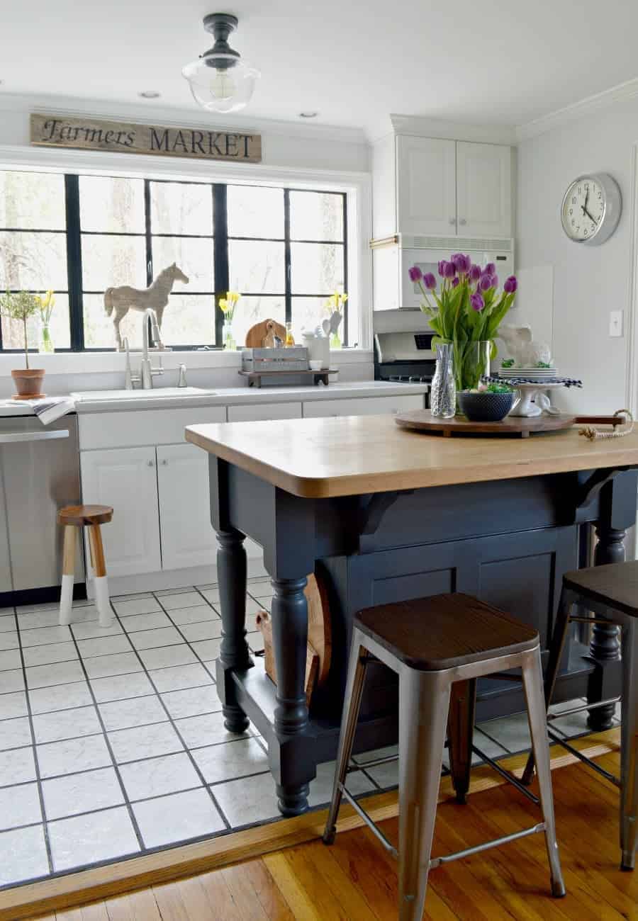 A kitchen with a spring vignette of purple tulips, white bunnies, and a navy bowl with candy eggs on a dark gray painted kitchen island