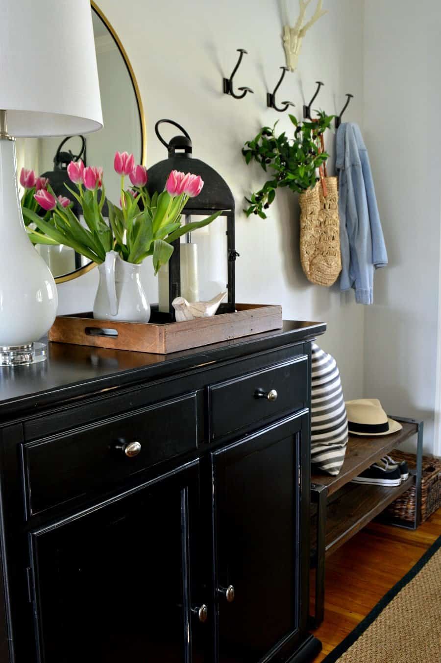 small entryway with pink tulips in pitcher on black cabinet