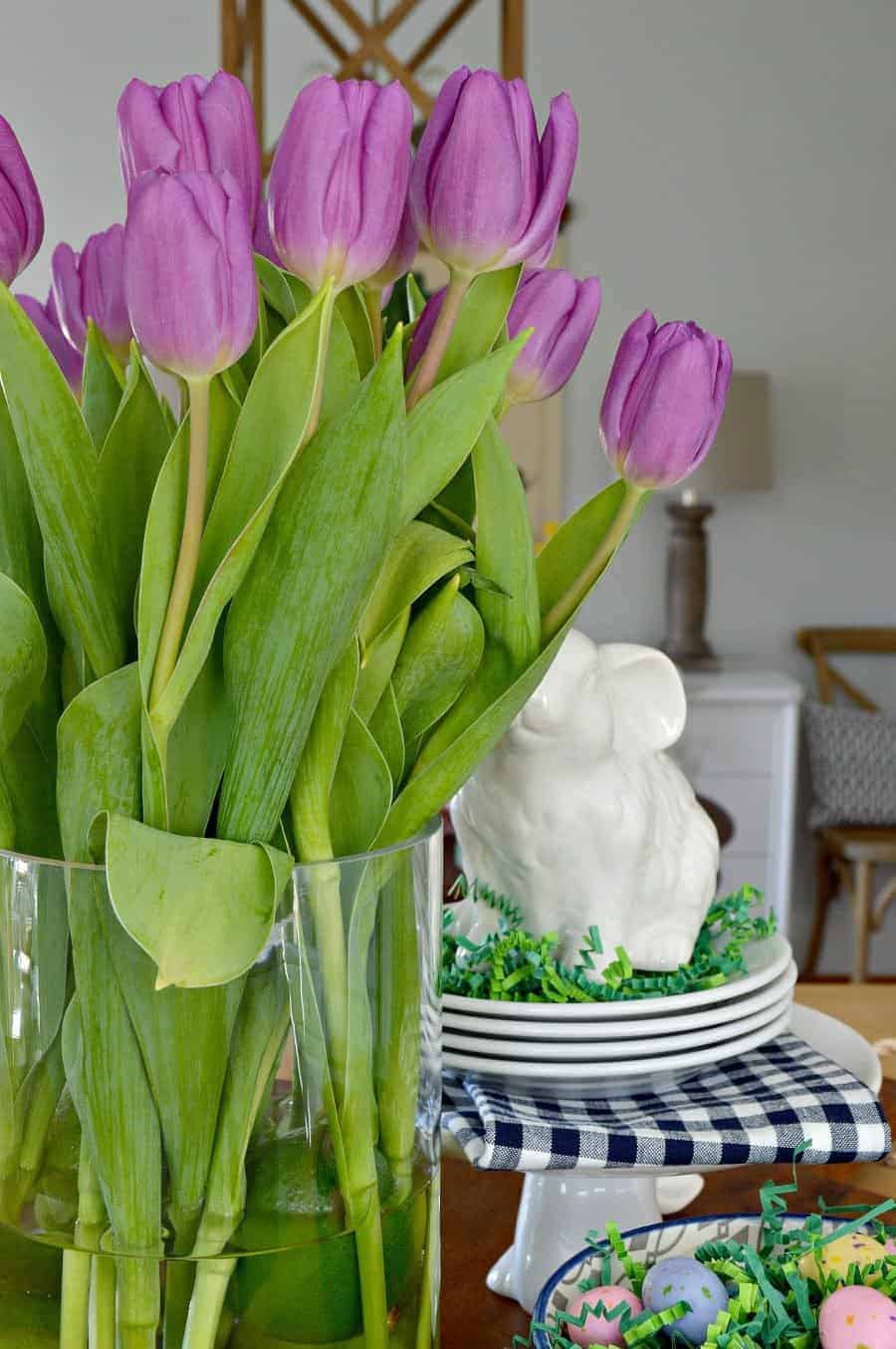 spring vignette with purple tulips, white bunnies, and a navy bowl with candy eggs