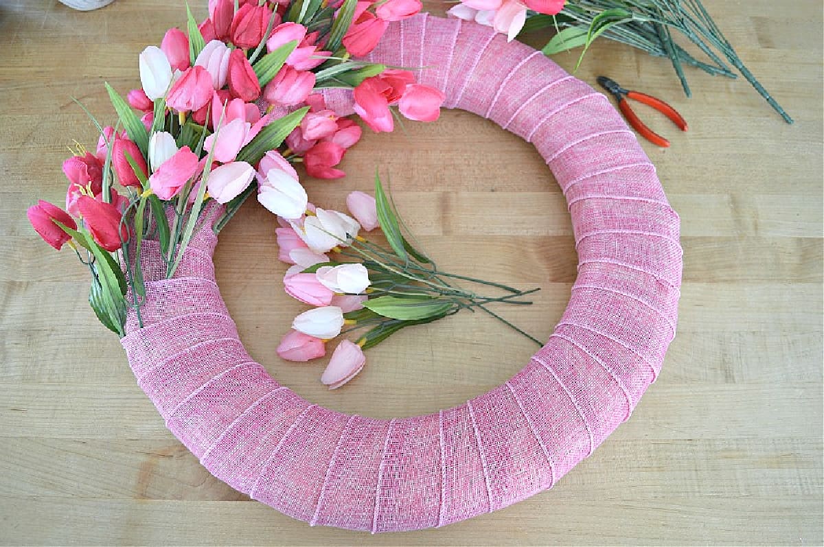 wreath form wrapped in pink ribbon with tulips added