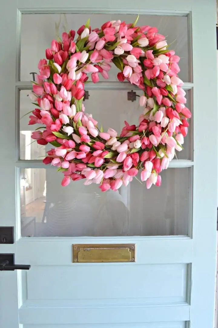 pink tulip wreath hanging on a blue farmhouse front door