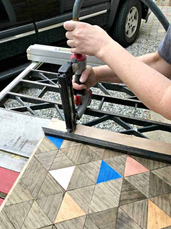 using staple gun to attach wood frame to artwork