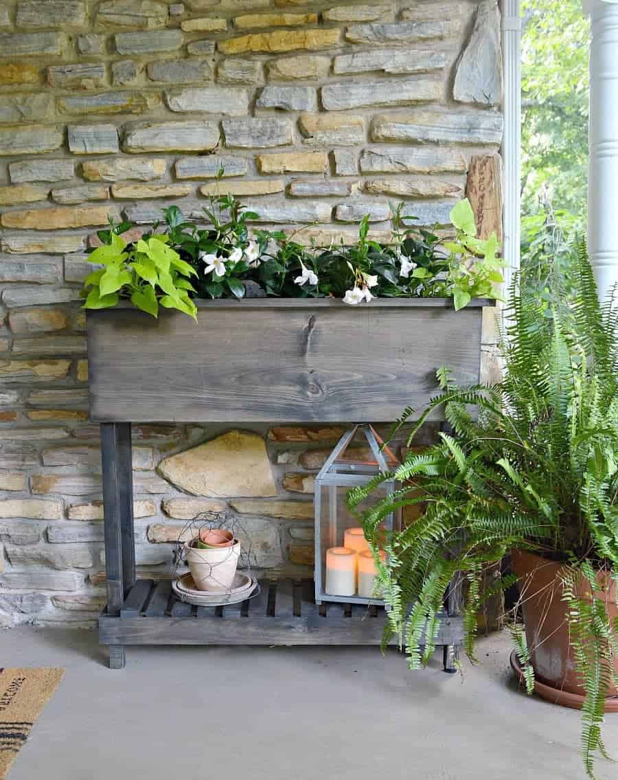 DIY raised planter box with legs on front porch of stone cottage