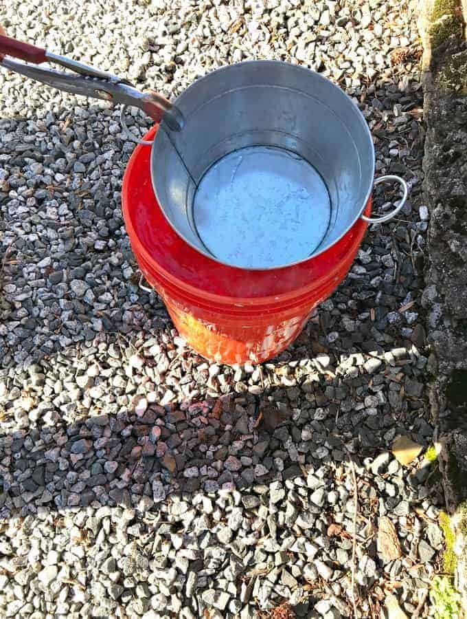 galvanized bucket getting dipped in bucket of water while making DIY succulent planter