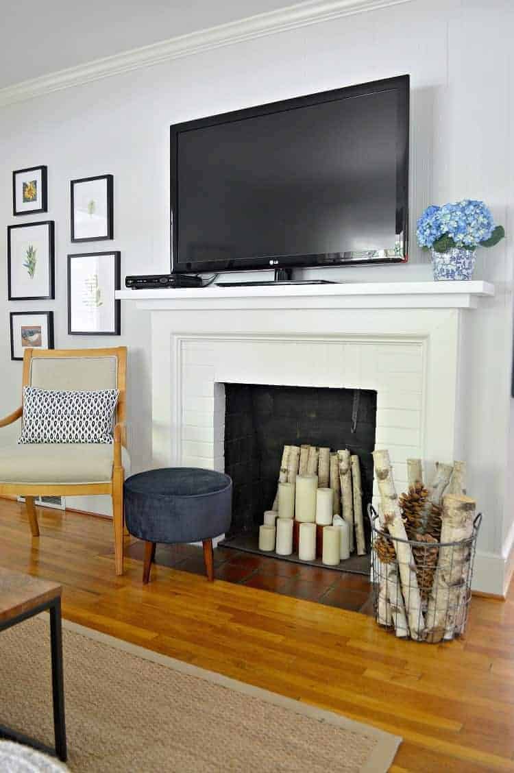 flat screen tv on white fireplace mantel with chair next to it