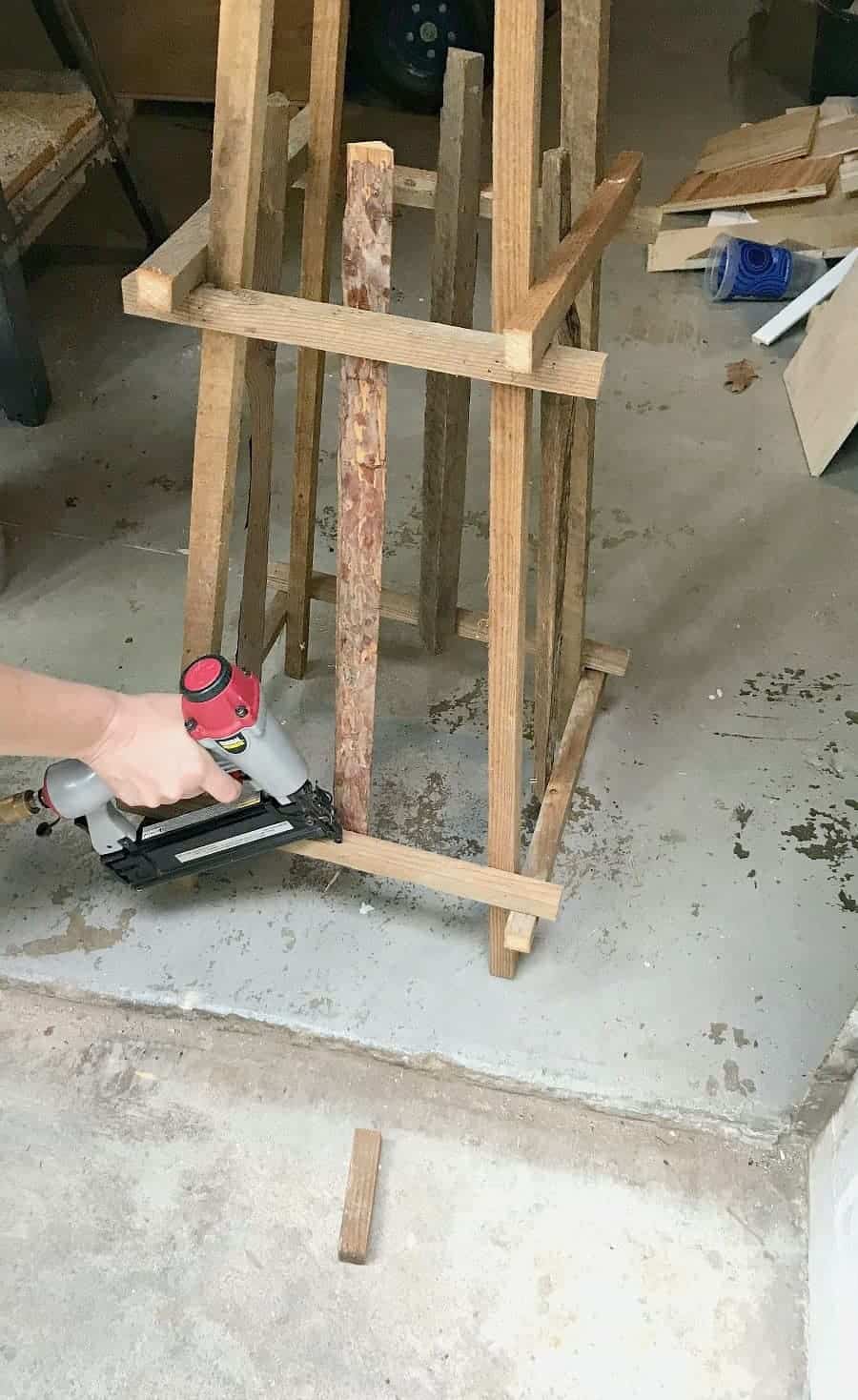 stapling brads into the wood on a wooden garden obelisk