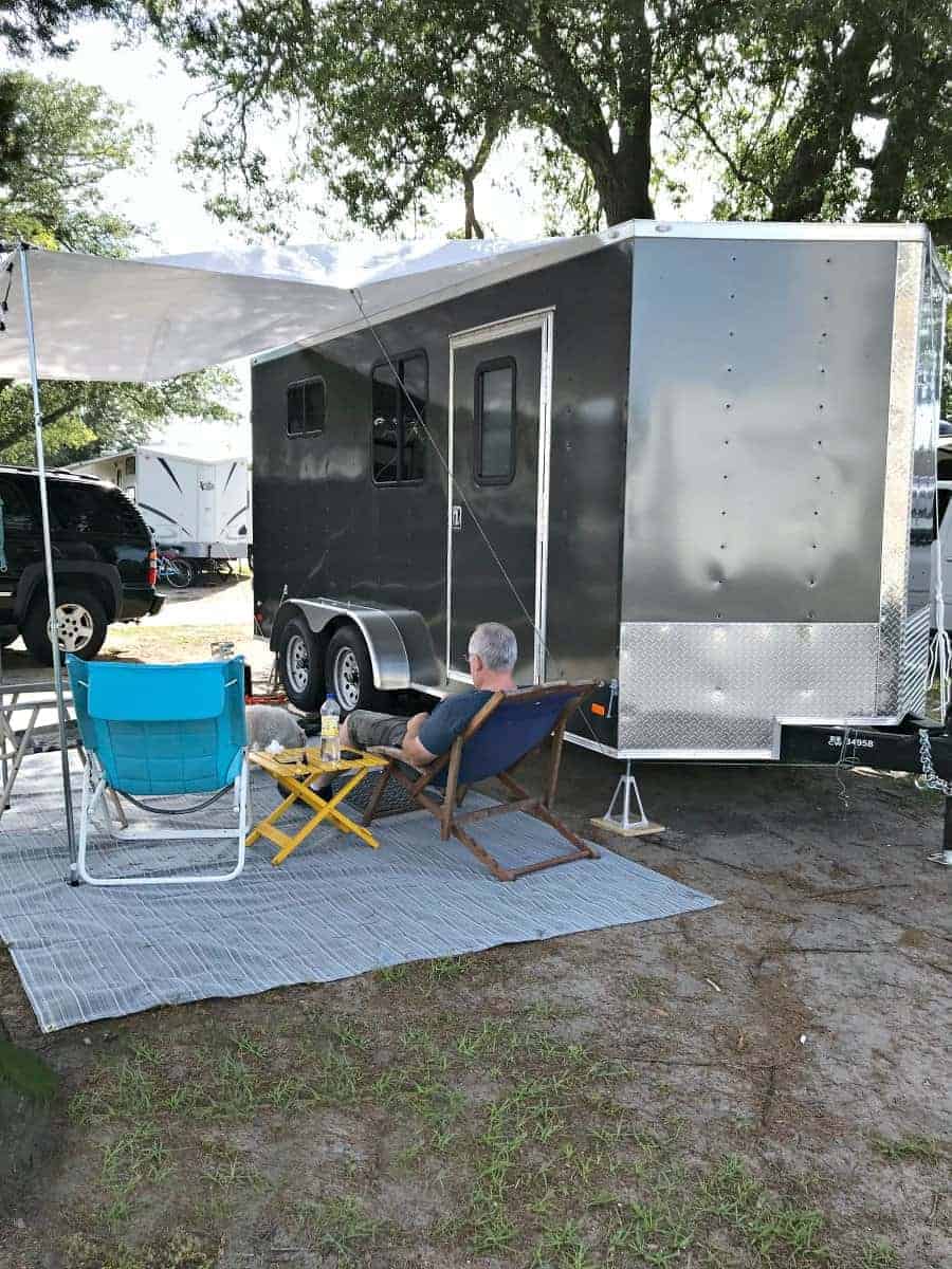 little RV set up for camping with chairs and white awning