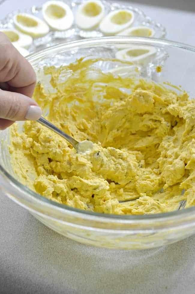 mixing up deviled eggs in large glass bowl