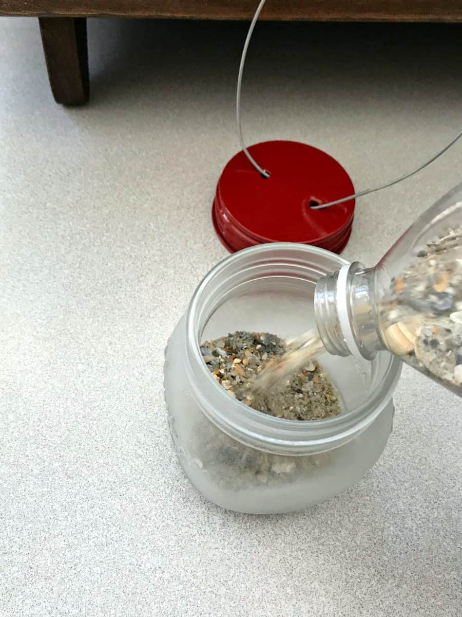 making DIY mason jar lanterns by adding sand to jar