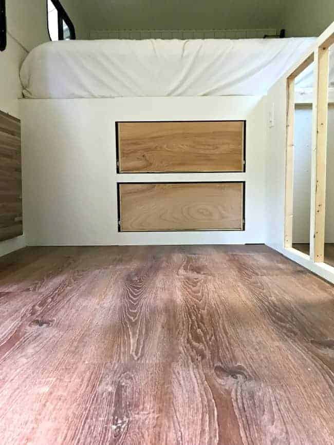 vinyl plank flooring in a small RV with bed in background