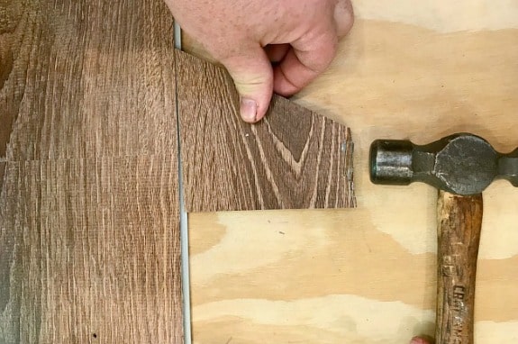 hammering a piece of vinyl plank floor during installation