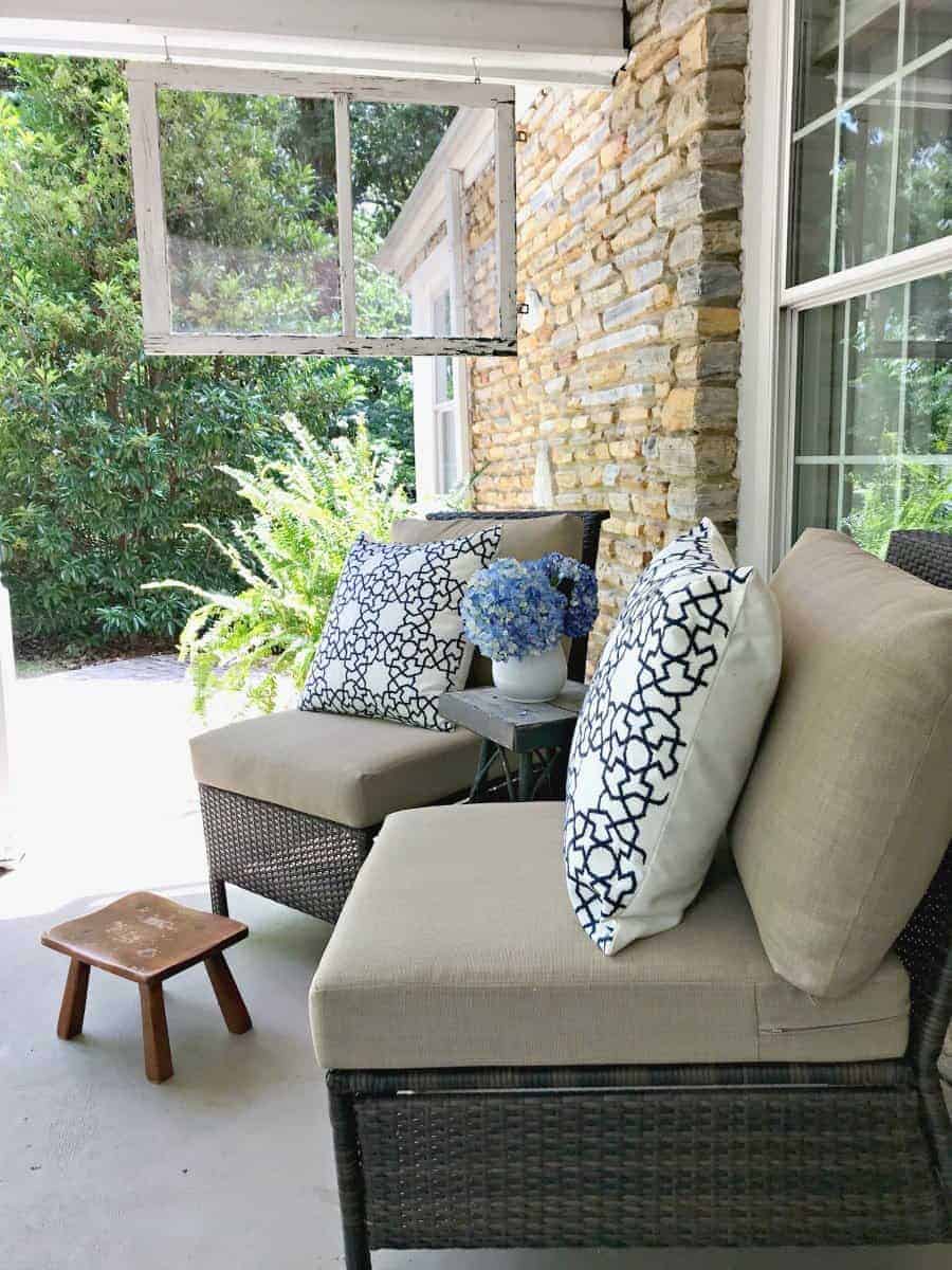 two wicker chairs on porch with blue and white pillows and a little footstool