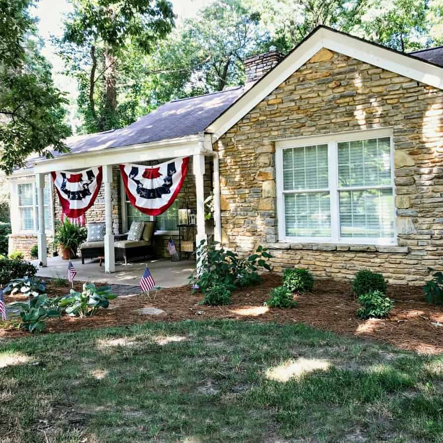 stone cottage with red, white and blue buntings hanging on covered front porch