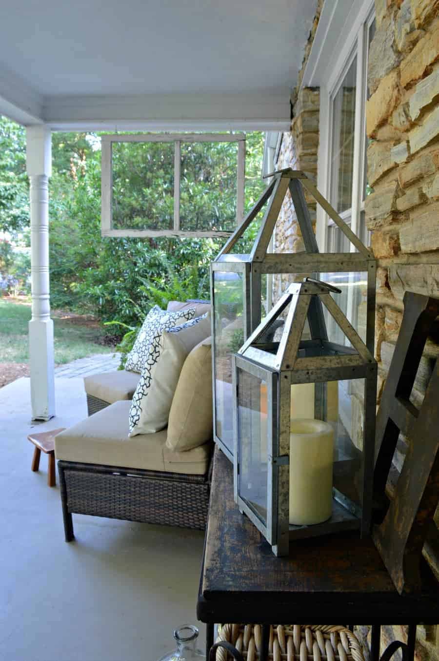 metal lanterns and the letter H on a wood table on a covered porch