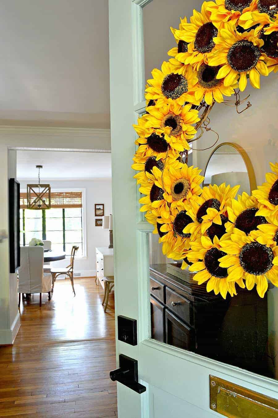 sunflower wreath hanging on turquoise front door with a view into a house