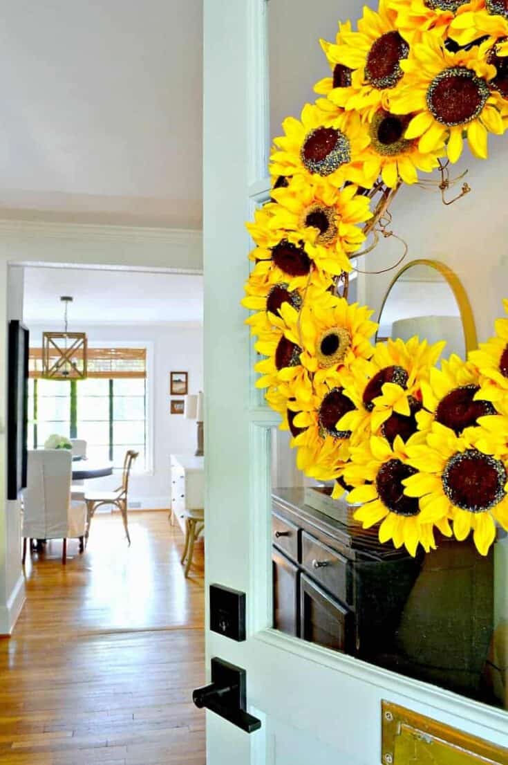 sunflower wreath hanging on turquoise front door with a view into a house